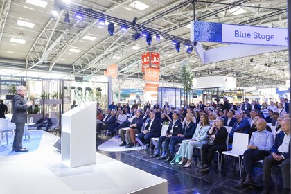 A speaker gives a presentation to a seated audience on the IFAT Munich Blue Stage.
