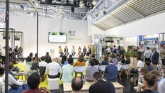 Publikum verfolgt eine Podiumsdiskussion mit sechs Personen auf der Bühne der IFAT Munich Green Stage.