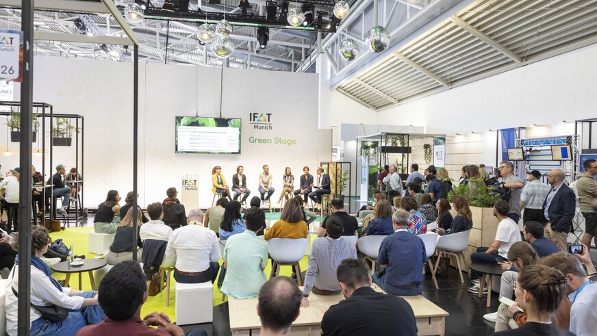 Publikum verfolgt eine Podiumsdiskussion mit sechs Personen auf der Bühne der IFAT Munich Green Stage.