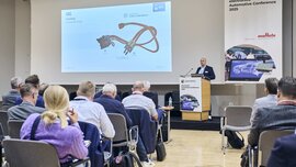 A man presents slides on automotive technology to an audience at the electronica Automotive Conference 2025.