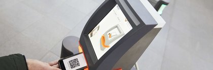 Mehrere Ticketscanner im Eingangsbereich der productronica. Eine Person hält ihr Smartphone mit QR-Code-Eintrittskarte unter das Gerät.