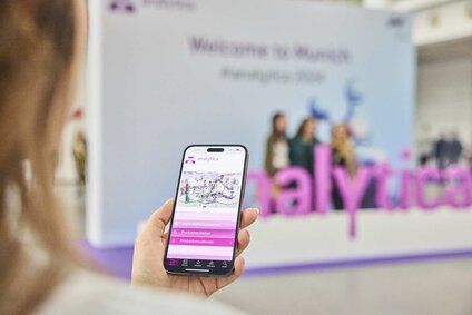auf dem Bild erkennt man ein Handy, dass vor einem großen Schriftzug, auf dem analytica steht, geöffnet ist, es hat die analytica App geöffnet 
