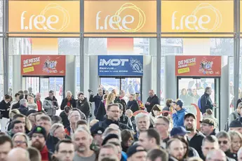 Large crowd in an entrance hall, banners for “f.re.e” and “IMOT” can be seen above the entrance.