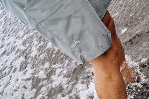 Ein Mann steht mit grauen Schöffel-Shorts im Wasser.