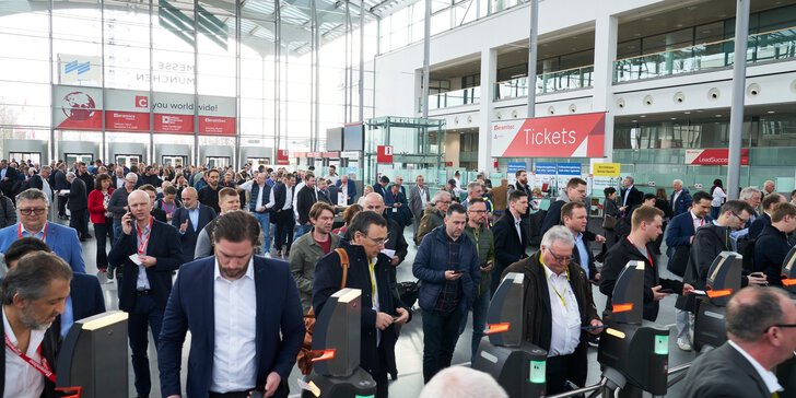 Numerous visitors to the trade fair are waiting in an entrance hall at Messe München in front of the security scanners to be admitted to ceramitec.