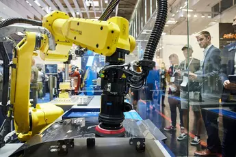 Visitors observe a robot at work during automatica 2022.