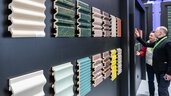 Different colored patterned and corrugated tiles on the wall of an exhibitor stand at BAU. Two men look at the samples.