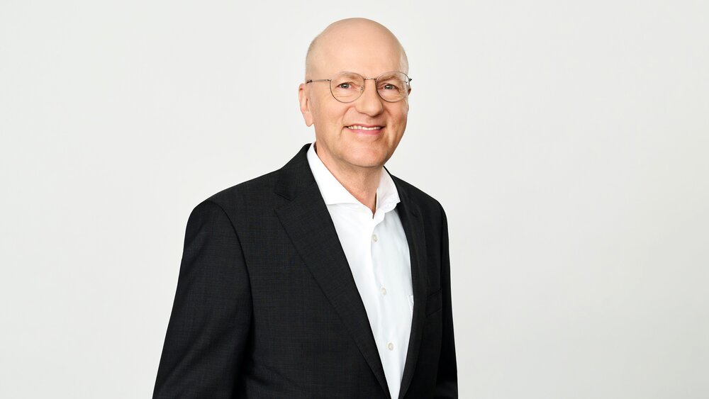 In the photo, you can see Dr. Pfeiffer, CEO of Messe München Group, wearing a suit and smiling.