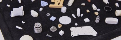 Various small 3D-printed objects and parts, displayed on a black tray.