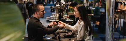 Two people are standing at a table at INHORGENTA trying on jewelry.