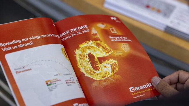 Eine Person hält ein Magazin mit einer Doppelseite über die ceramitec 2026 in den Händen.