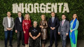 Eight people stand smiling in front of a green wall of plants with the word INHORGENTA spelled out in white flowers.