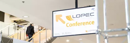 Schild für die LOPEC-Konferenz neben einer Rolltreppe in einem modernen Gebäude.