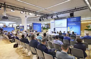 Gruppe von Menschen sitzt in einem Raum und hört einem Vortrag beim Bauma Forum 2022 zu.