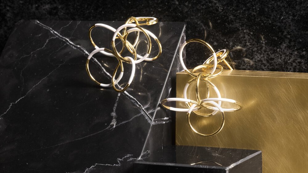 Elegant interlocking rings in gold and white on marble and brass surfaces.