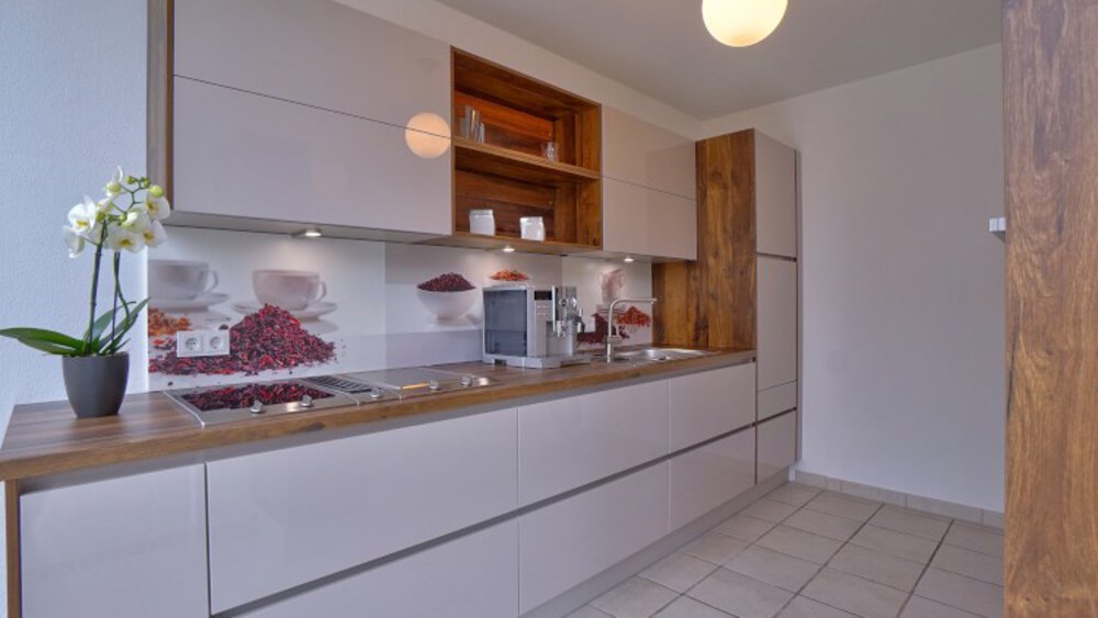 Moderne Küche mit eleganten Schränken, einer Holzarbeitsplatte, einer Orchideenpflanze und einer runden Deckenleuchte.