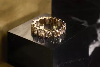 Goldring mit geometrischem Design auf dunkler Marmoroberfläche.