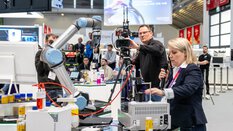 a woman demonstrates the function of a laboratory device and is filmed by a man