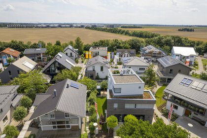 Luftaufnahme des Bauzentrum Poing mit modernen Häusern, grünen Rasenflächen und umliegenden Feldern.