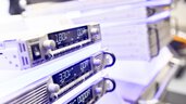 Close-up of three power modules for server racks displayed on top of each other at a trade fair stand.
