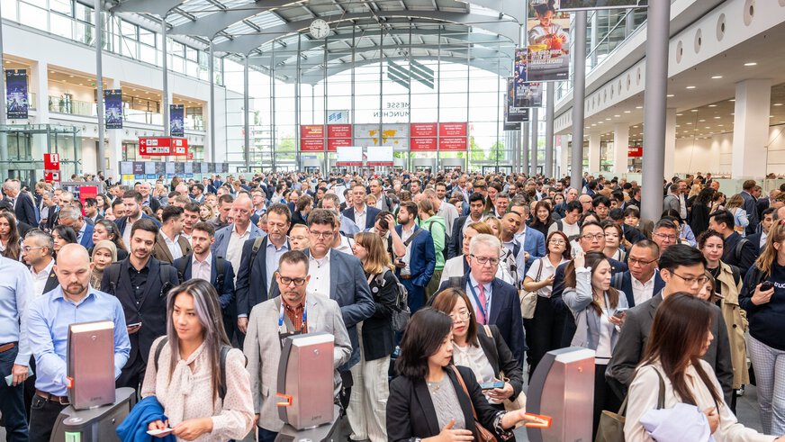 Eine große Menschenmenge wartet in der Eingangshalle West, um an den Drehkreuzen in die Messehallen der Transport Logistic 2025 zu kommen.
