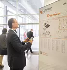 A man looks at the LOPEC overview map at the entrance to the trade fair, people walk past in the background.