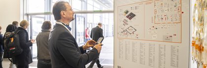 Ein Mann betrachtet den LOPEC Übersichtsplan am Eingang der Messe, im Hintergrund laufen Menschen vorbei.