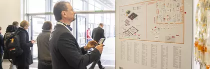 Ein Mann betrachtet den LOPEC Übersichtsplan am Eingang der Messe, im Hintergrund laufen Menschen vorbei.