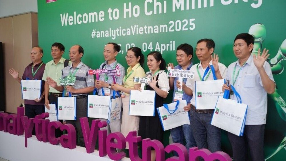 A group of people pose with gift bags at the analytica Vietnam 2025 event in Ho Chi Minh City.