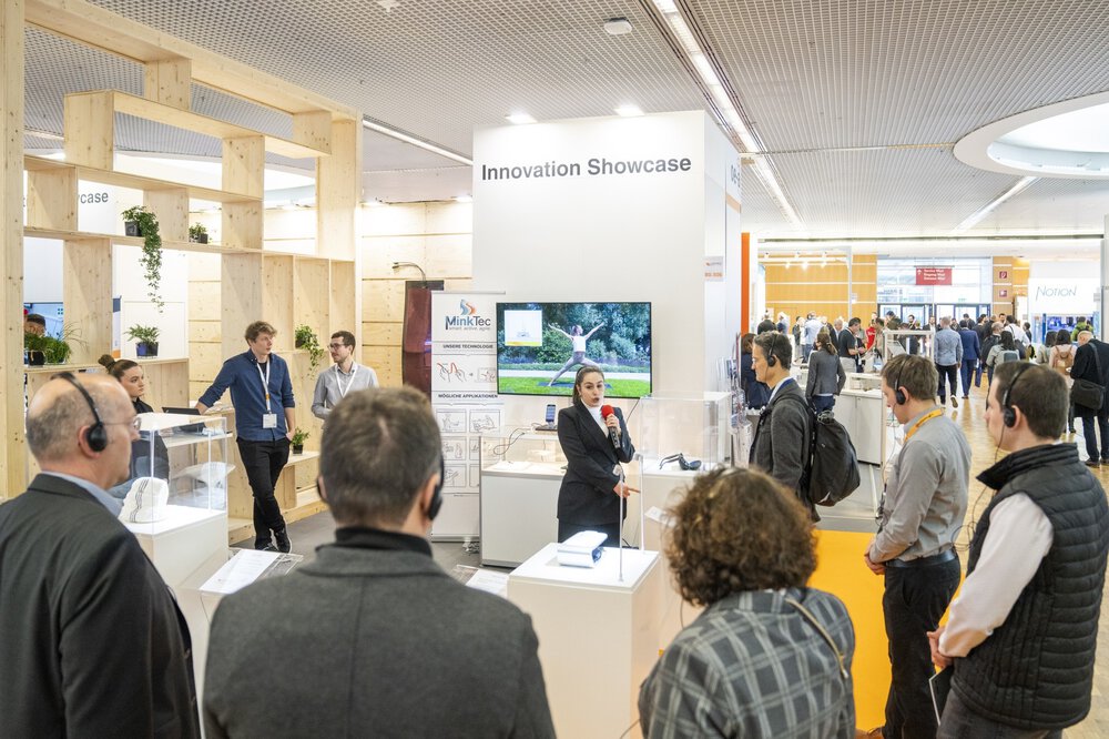 People gathered around a presentation at a stand labeled “Innovation Showcase” with displays and screens.