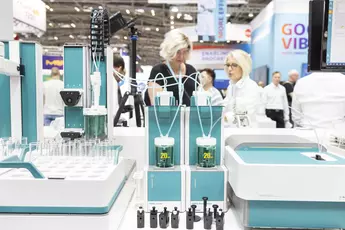 A laboratory apparatus in shades of green and white with liquid in two containers - for a Karl Fischer titration or thermometric titration - on an exhibition stand.