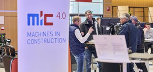 Laughing trade fair visitors in discussion at the MiC 4.0 – Machines in Construction booth.