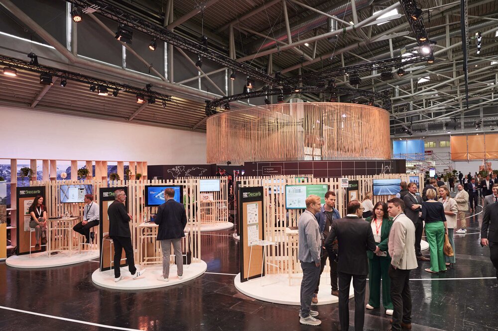 People stand in groups at various round exhibition stands in the EXPO REAL Decarb area.