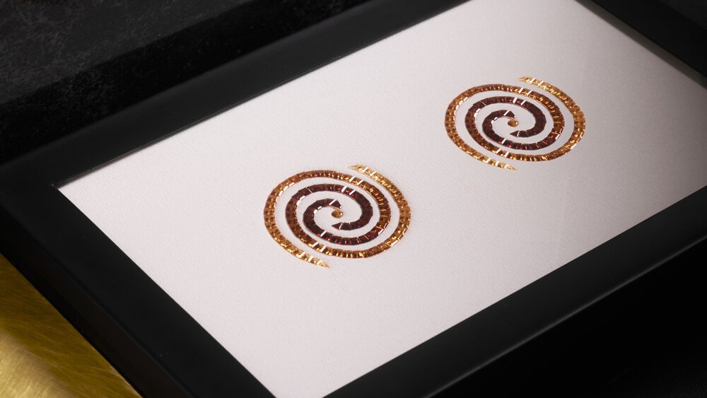 Framed artwork with two brown spiral designs on a white background.