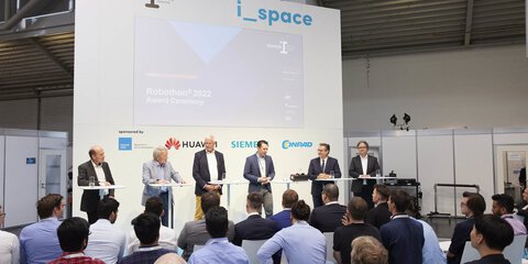 Panel discussion between 6 people on the i_space stage in front of a seated audience.