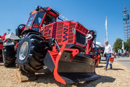 A red special forestry tractor stands jacked up on the open-air site of Messe München during INTERFORST.