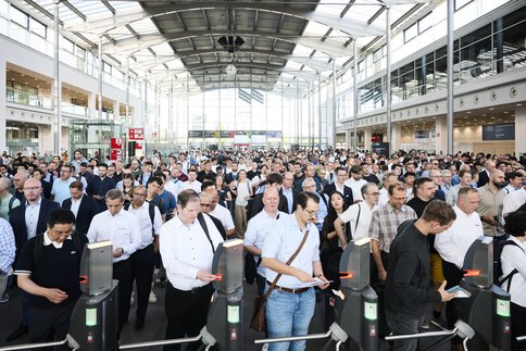 Die Eingangshalle der Laser World of Photonics 2025 ist gefüllt mit einer beeindruckenden Anzahl von Fachbesucherinnen und -besuchern, die gespannt auf den Einlass warten.