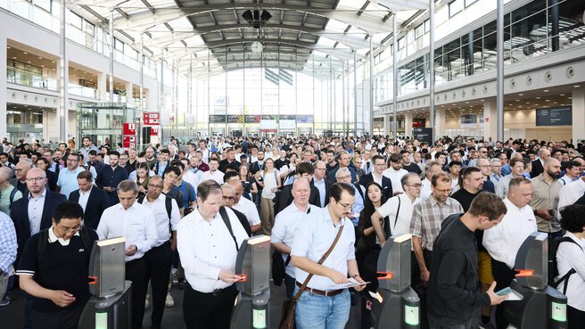 Die Eingangshalle der Laser World of Photonics 2025 ist gefüllt mit einer beeindruckenden Anzahl von Fachbesucherinnen und -besuchern, die gespannt auf den Einlass warten.