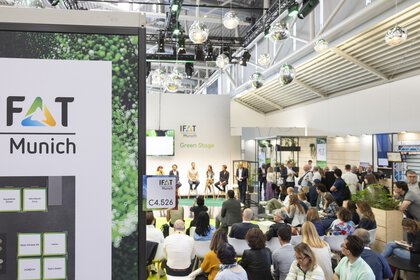 Audience at a panel discussion on the Green Stage at IFAT Munich with six people on stage.