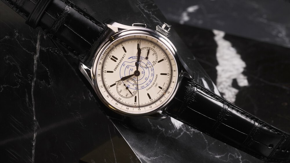 Elegant wristwatch from Eberhard&Co. with a cream-coloured dial and black leather strap, presented on a dark marble surface.
