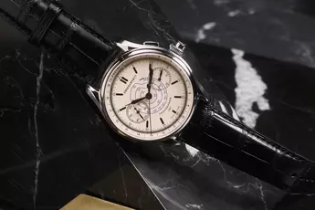 Elegante Armbanduhr von Eberhard&Co. mit cremefarbenem Zifferblatt und schwarzem Lederarmband, präsentiert auf einer dunklen Marmoroberfläche.