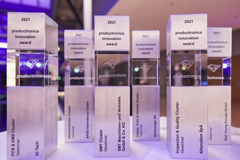 Lined up trophies made of metal and glass with 3D engraving of the productronica logo, the inscription 