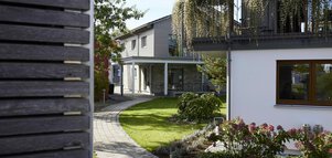 Modernes Haus mit gepflastertem Weg, grünem Rasen und üppigem Garten.