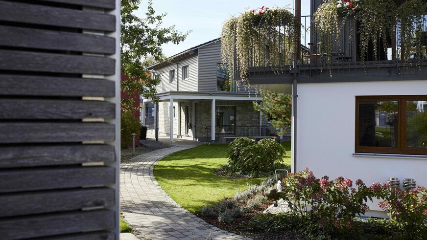Modernes Haus mit gepflastertem Weg, grünem Rasen und üppigem Garten.