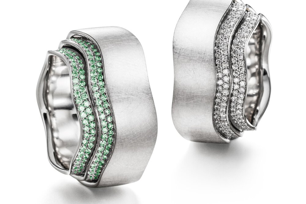 Zwei kunstvolle, nahezu identische gewellte Ringe aus Silber und mit vielen kleinen Diamanten besetzt, der eine mit Grünen und der andere mit Weißen.