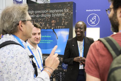 Experts chatting at a booth about precise optics technology used in biophotonics and laser medical technology.