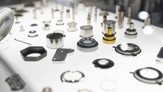 Gepresste Linsen und Gummidichtungen werden während der productronica auf einer weißen Oberfläche präsentiert.