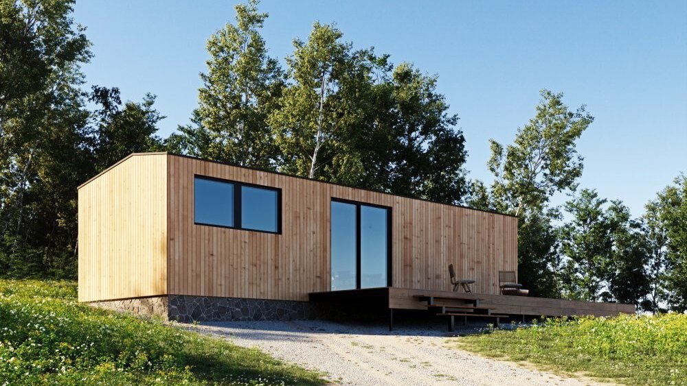 Moderne Holzhütte mit großen Fenstern, inmitten einer Grasfläche mit umgebenden Bäumen unter einem klaren blauen Himmel.