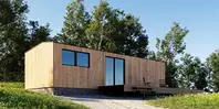 Moderne Holzhütte mit großen Fenstern, inmitten einer Grasfläche mit umgebenden Bäumen unter einem klaren blauen Himmel.