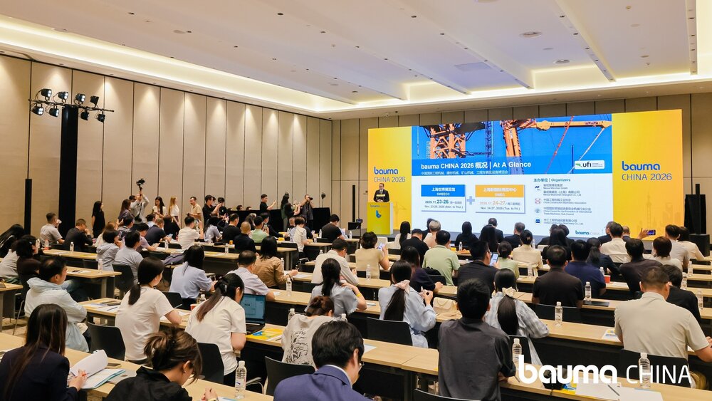 A large conference room in which a large number of people are seated, watching a presentation on bauma CHINA 2026, which is being shown on a large screen at the front of the room.